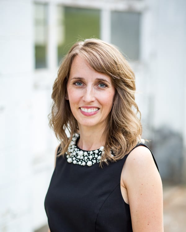Teresa Huff headshot, black dress, white brick
